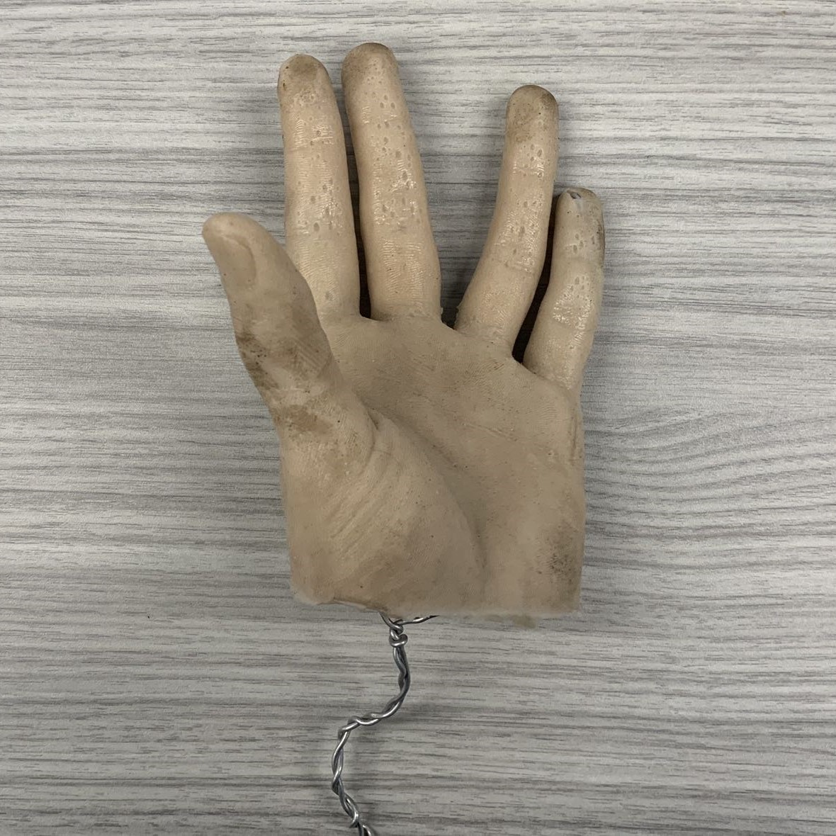 Rubber hand with metal brackets inside to allow for finger movement. The surface is slightly sticky, so there is dust attached to it. There are also some small holes on the surface. With a little bit of reflection.